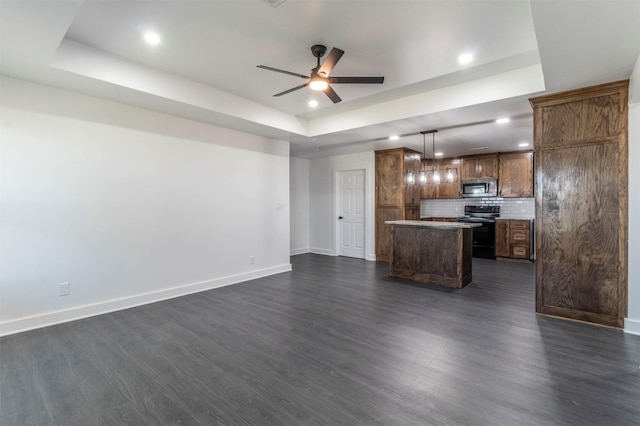 kitchen with a kitchen island, a tray ceiling, black electric range, stainless steel microwave, and open floor plan