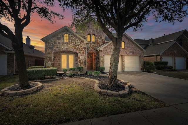 view of front facade with brick siding, french doors, driveway, stone siding, and an attached garage