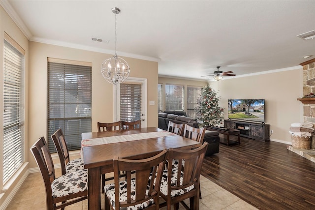 tiled dining space featuring ceiling fan with notable chandelier and ornamental molding