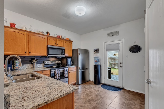 kitchen with sink, stainless steel appliances, light stone counters, a textured ceiling, and light tile patterned floors