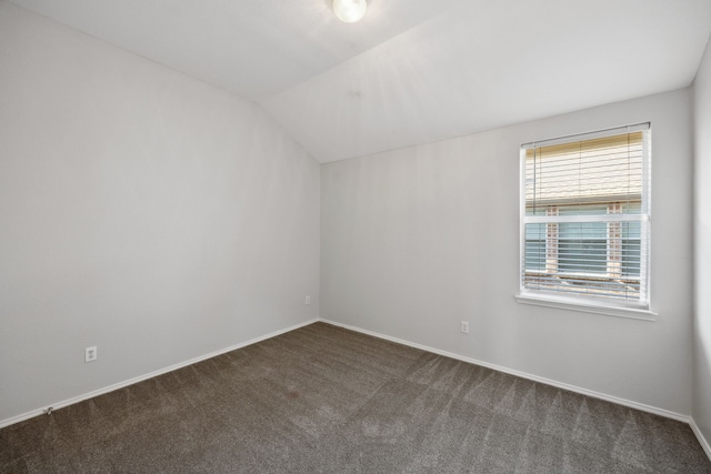 carpeted spare room featuring lofted ceiling