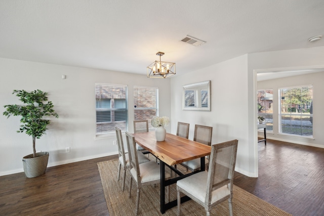 dining room featuring a healthy amount of sunlight, dark wood-type flooring, and an inviting chandelier