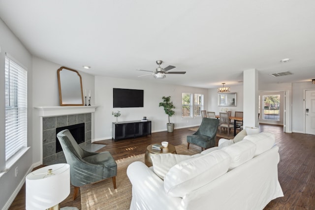 living room with a tiled fireplace, dark hardwood / wood-style floors, and ceiling fan