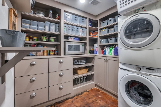 clothes washing area featuring cabinets and stacked washer / drying machine