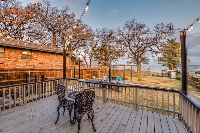 wooden deck featuring a water view and a lawn