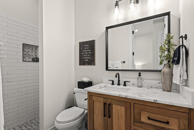 bathroom with vanity, toilet, and tiled shower