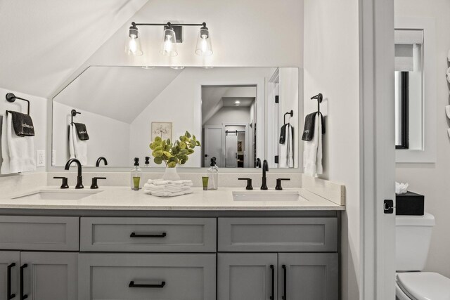 bathroom with vanity, toilet, and vaulted ceiling