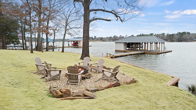 dock area featuring a lawn, a water view, and a fire pit