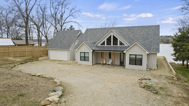 modern farmhouse style home with covered porch, a water view, and a garage