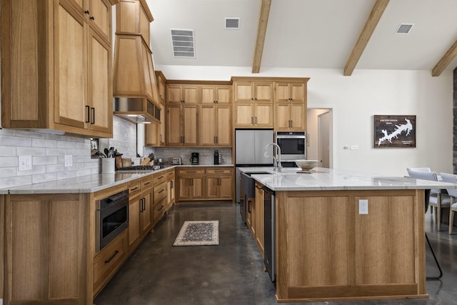 kitchen featuring a center island with sink, light stone countertops, appliances with stainless steel finishes, tasteful backsplash, and beam ceiling