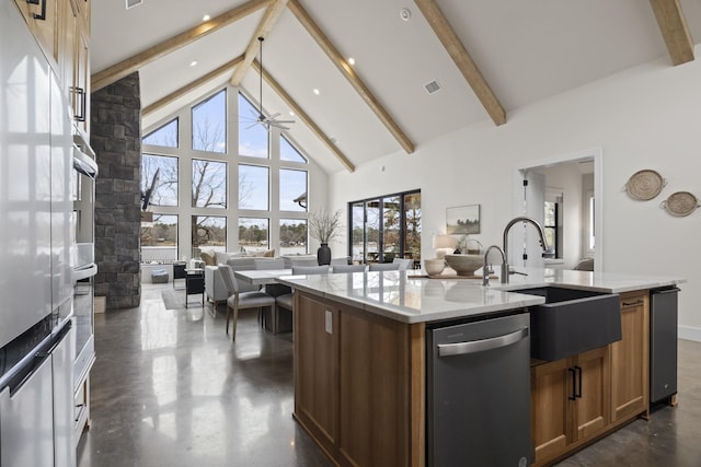 kitchen featuring high vaulted ceiling, sink, an island with sink, appliances with stainless steel finishes, and beam ceiling