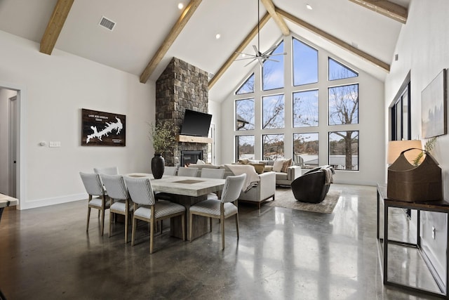 dining space featuring beam ceiling, a stone fireplace, ceiling fan, and high vaulted ceiling