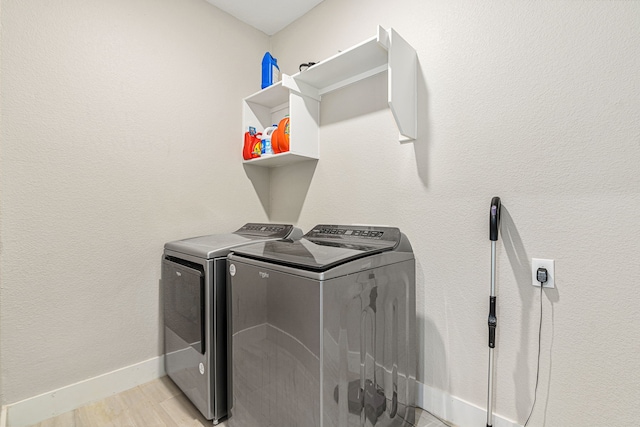 laundry area with light hardwood / wood-style floors and washing machine and clothes dryer