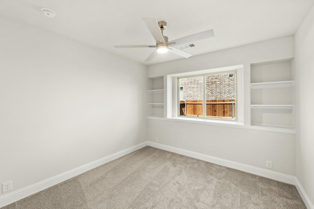 carpeted spare room with built in features, ceiling fan, baseboards, and visible vents