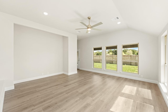 empty room featuring light wood-style flooring, vaulted ceiling, a ceiling fan, and visible vents