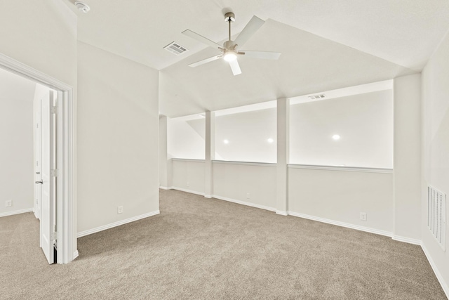 carpeted spare room with vaulted ceiling, a ceiling fan, and visible vents