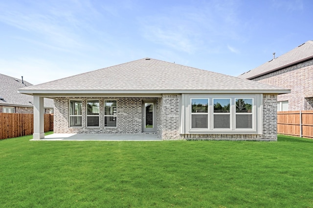 rear view of house featuring roof with shingles, brick siding, and a yard