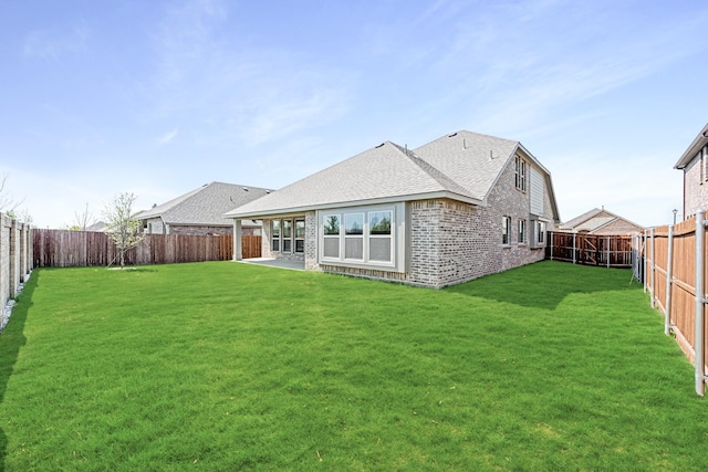 back of house featuring a yard, a fenced backyard, roof with shingles, a patio area, and brick siding