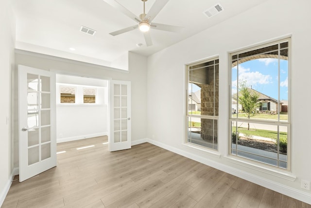 empty room with baseboards, french doors, a ceiling fan, light wood-style floors, and visible vents