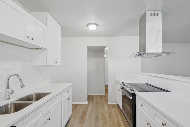 kitchen with island exhaust hood, sink, electric stove, light hardwood / wood-style floors, and white cabinetry