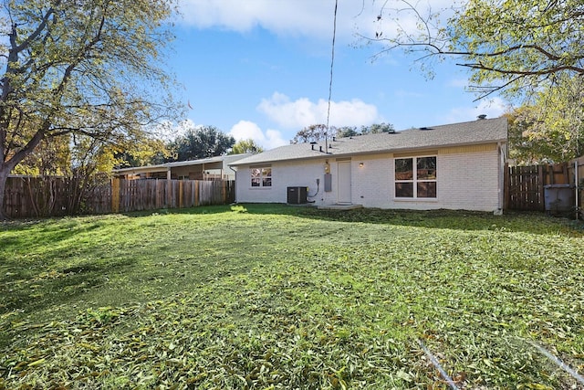 rear view of property with cooling unit and a yard