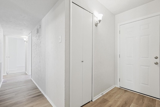 hallway featuring light hardwood / wood-style floors and a textured ceiling