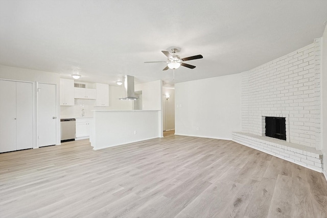 unfurnished living room featuring ceiling fan, light hardwood / wood-style floors, and a brick fireplace