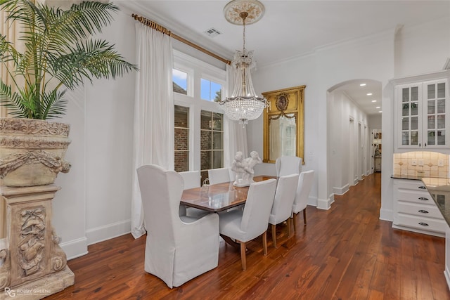 dining space with dark hardwood / wood-style flooring, ornamental molding, and a chandelier