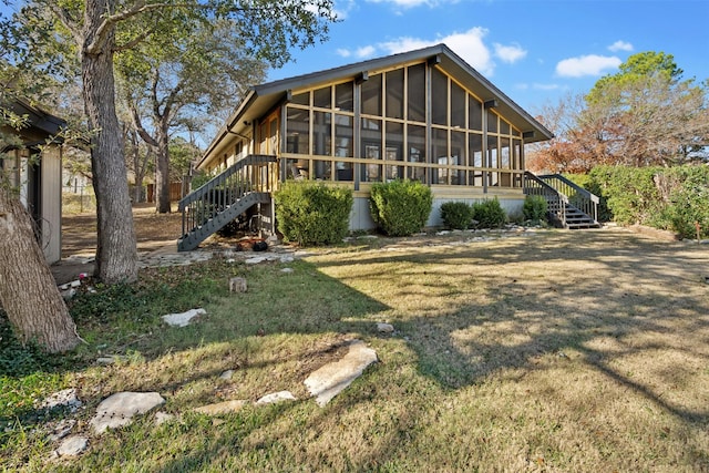 rear view of property with a sunroom and a yard