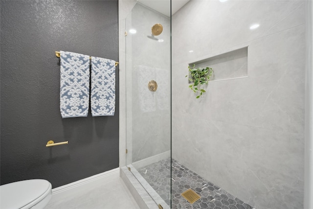 bathroom featuring a tile shower and toilet