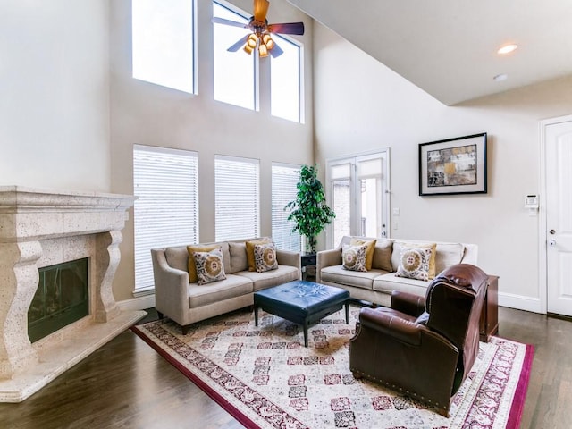 living room with a high ceiling, a fireplace, ceiling fan, and wood-type flooring