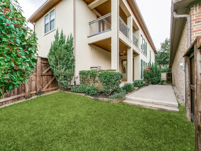 rear view of house with a lawn, a patio area, and a balcony