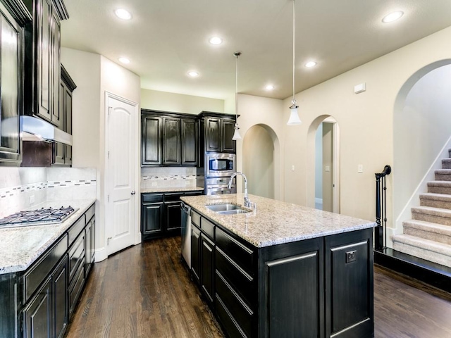 kitchen with pendant lighting, dark hardwood / wood-style floors, an island with sink, tasteful backsplash, and sink