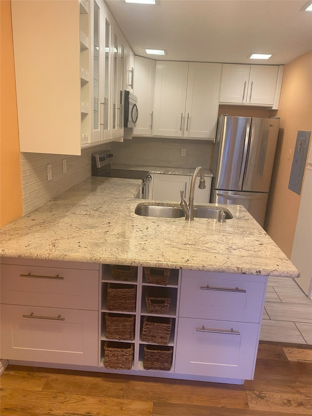 kitchen with sink, light stone counters, appliances with stainless steel finishes, white cabinets, and light wood-type flooring