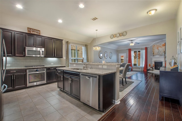 kitchen with a wealth of natural light, light hardwood / wood-style floors, hanging light fixtures, and appliances with stainless steel finishes