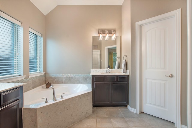 bathroom with tile patterned flooring, vanity, a relaxing tiled tub, and vaulted ceiling