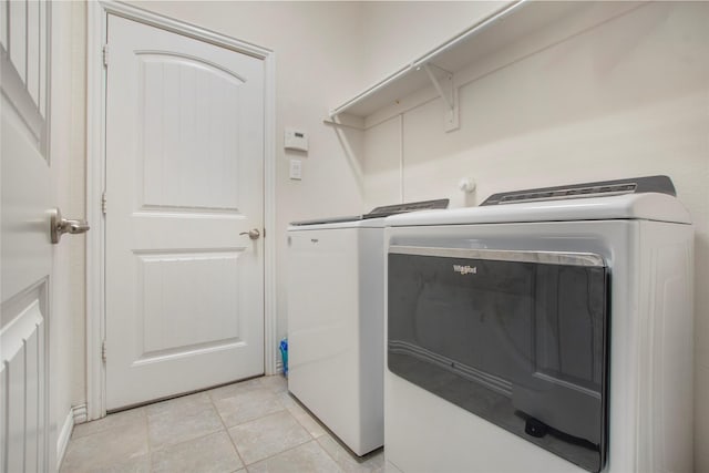 laundry area with independent washer and dryer and light tile patterned floors