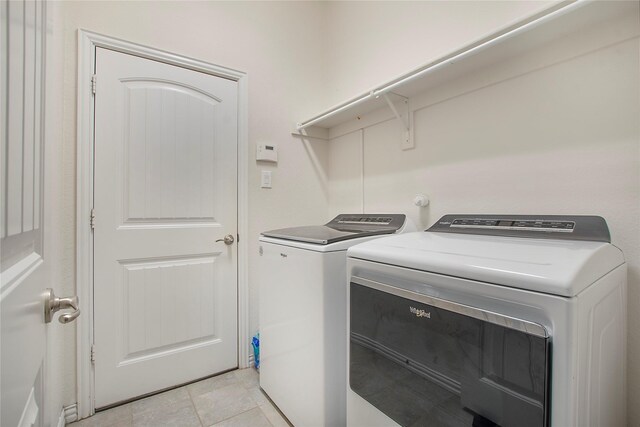 laundry area with washing machine and clothes dryer and light tile patterned floors