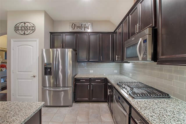 kitchen featuring light stone countertops, backsplash, stainless steel appliances, and dark brown cabinetry