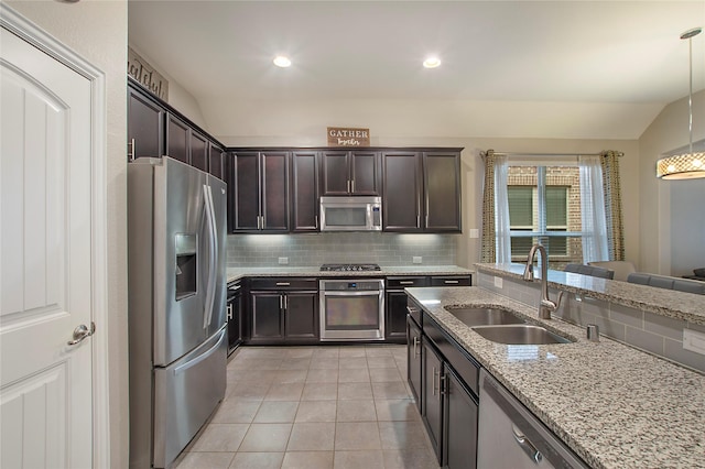 kitchen featuring sink, stainless steel appliances, light stone counters, pendant lighting, and vaulted ceiling