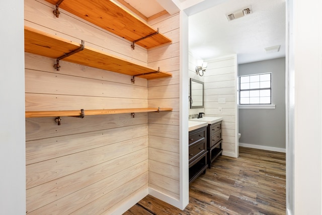 bathroom featuring hardwood / wood-style floors, vanity, toilet, and wood walls