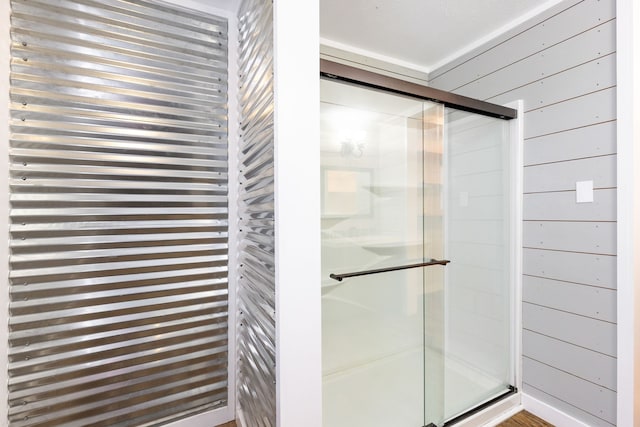 bathroom with wooden walls and a shower with shower door