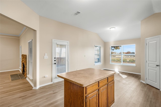 kitchen with a healthy amount of sunlight, lofted ceiling, a center island, and light hardwood / wood-style floors