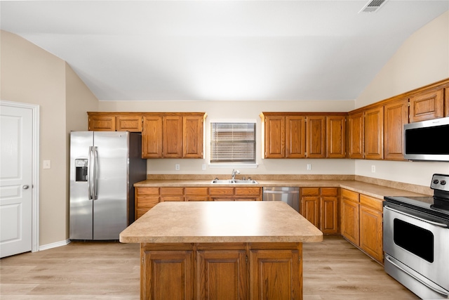 kitchen featuring stainless steel appliances, vaulted ceiling, a kitchen island, and sink