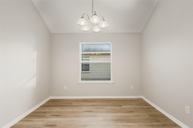 empty room featuring a chandelier and light wood-type flooring