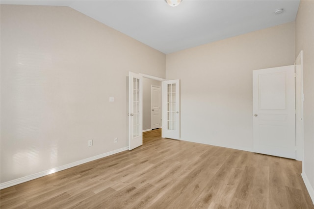 spare room featuring lofted ceiling, light hardwood / wood-style flooring, and french doors