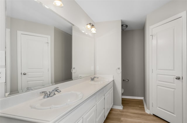 bathroom with hardwood / wood-style flooring, vanity, and toilet