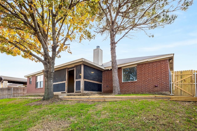 back of property featuring a sunroom and a lawn