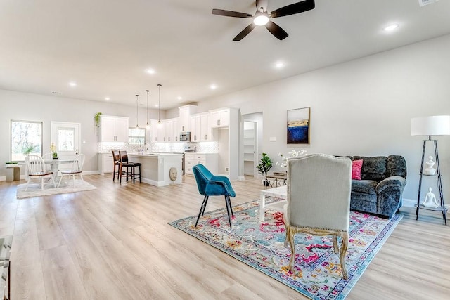 living room with ceiling fan, light hardwood / wood-style flooring, and sink