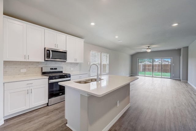 kitchen with white cabinets, appliances with stainless steel finishes, sink, and a kitchen island with sink